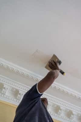 artisan qui applique de l'enduit sur le plafond