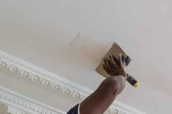 artisan qui applique de l'enduit sur le plafond